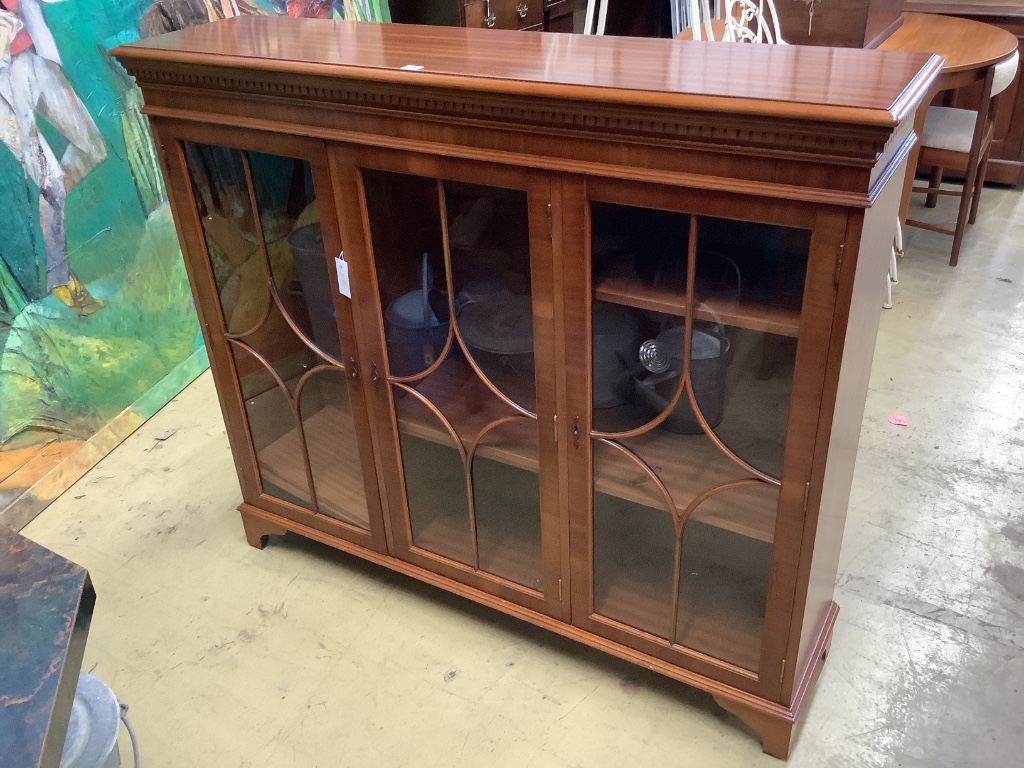 A reproduction mahogany three door bookcase, width 135cm depth 33cm height 116cm